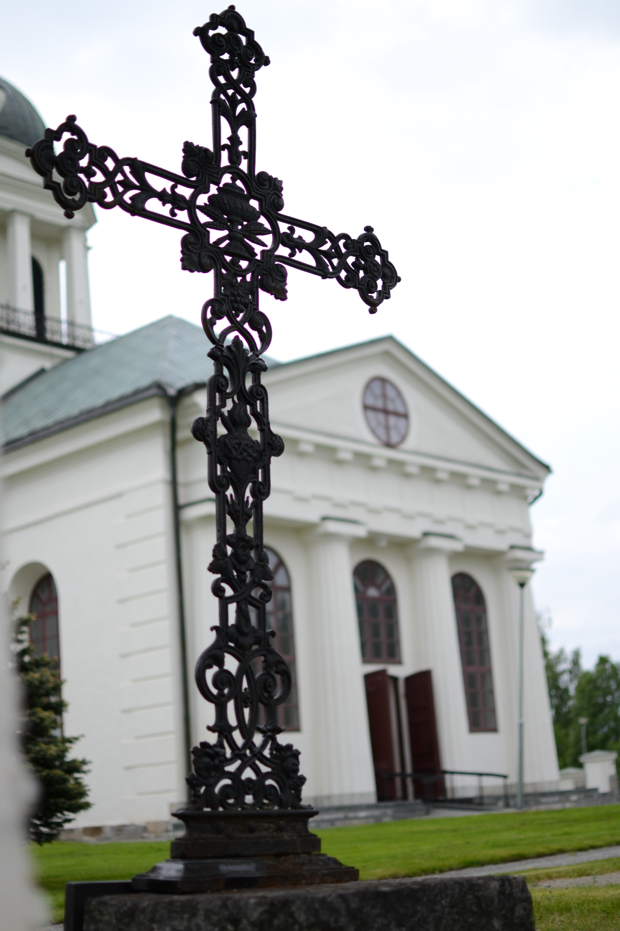 Restaurerat gjutjärnskors framför kyrka
